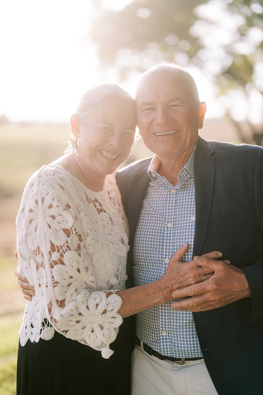 Smiling senior couple embracing outdoors in warm sunset light at a private estate wedding near Chatham-Kent, Ontario, Canada.