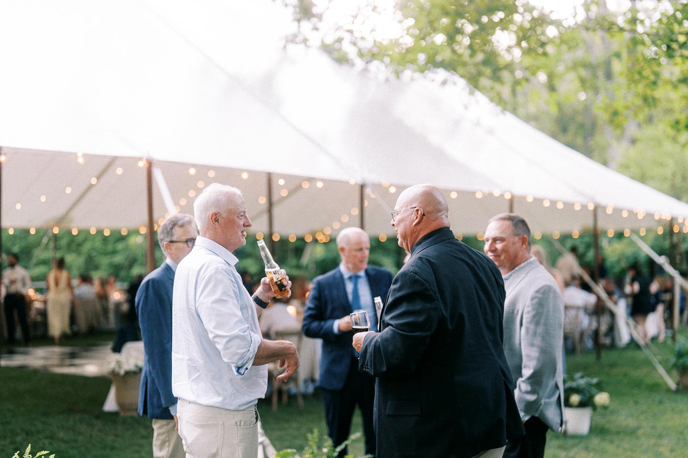 Guests talking with drinks outside a white wedding tent on a private estate near Chatham-Kent, Ontario.