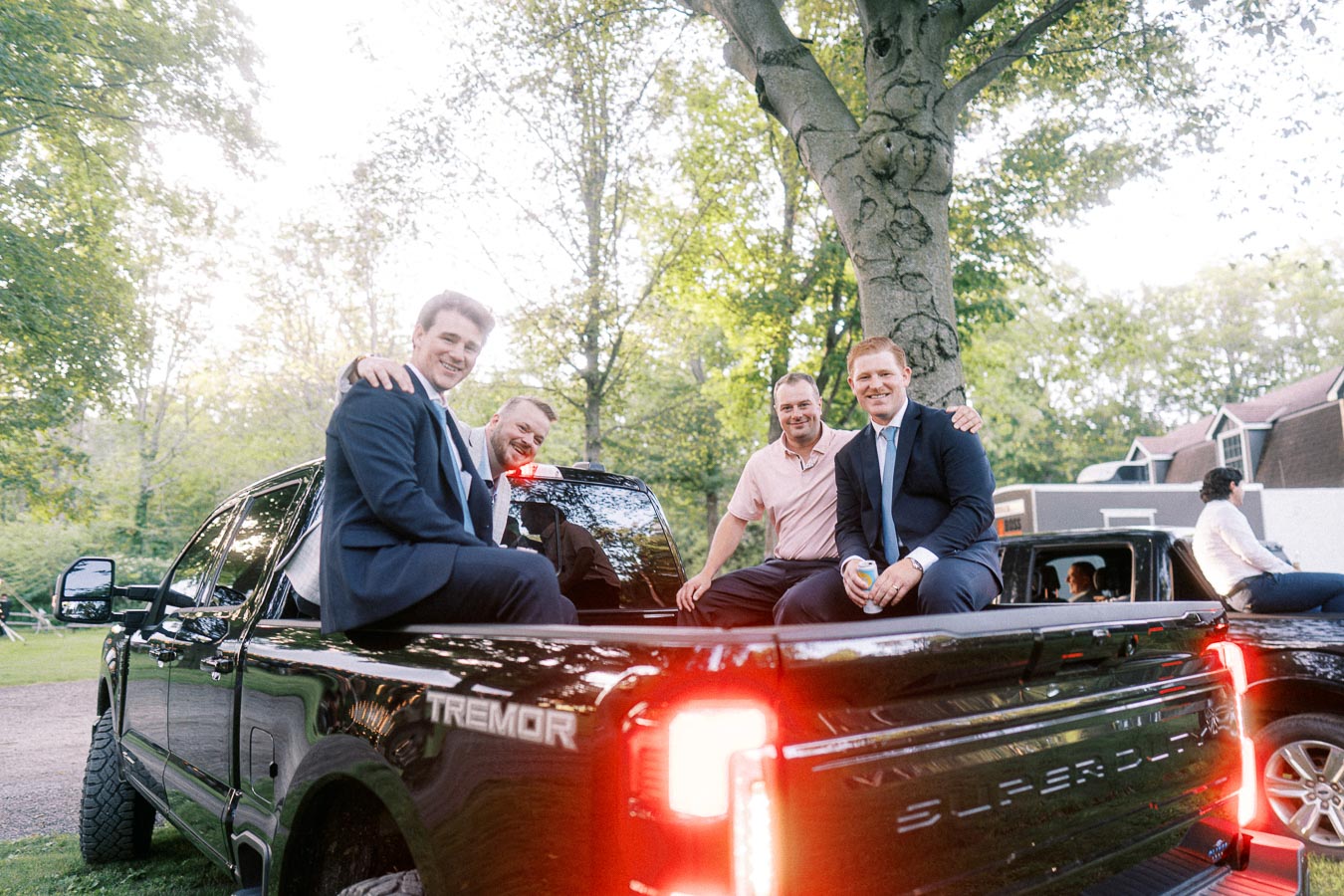 Wedding guests in suits sit in the bed of a black Ford Super Duty Tremor pickup truck on a private estate near Chatham-Kent, Ontario.