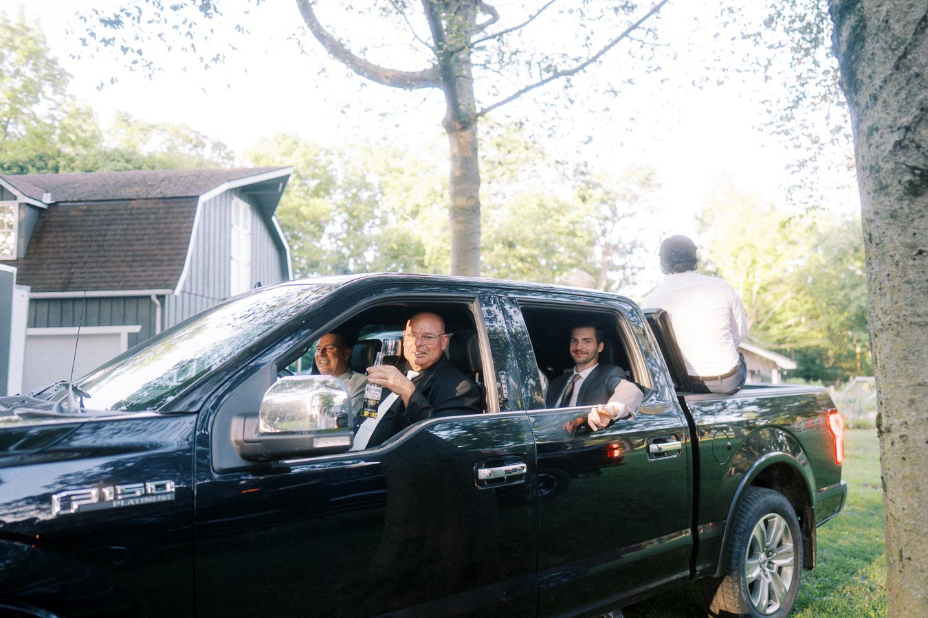 Men in suits riding in a black Ford F-150 with champagne on a private farm property near Chatham-Kent, Ontario.