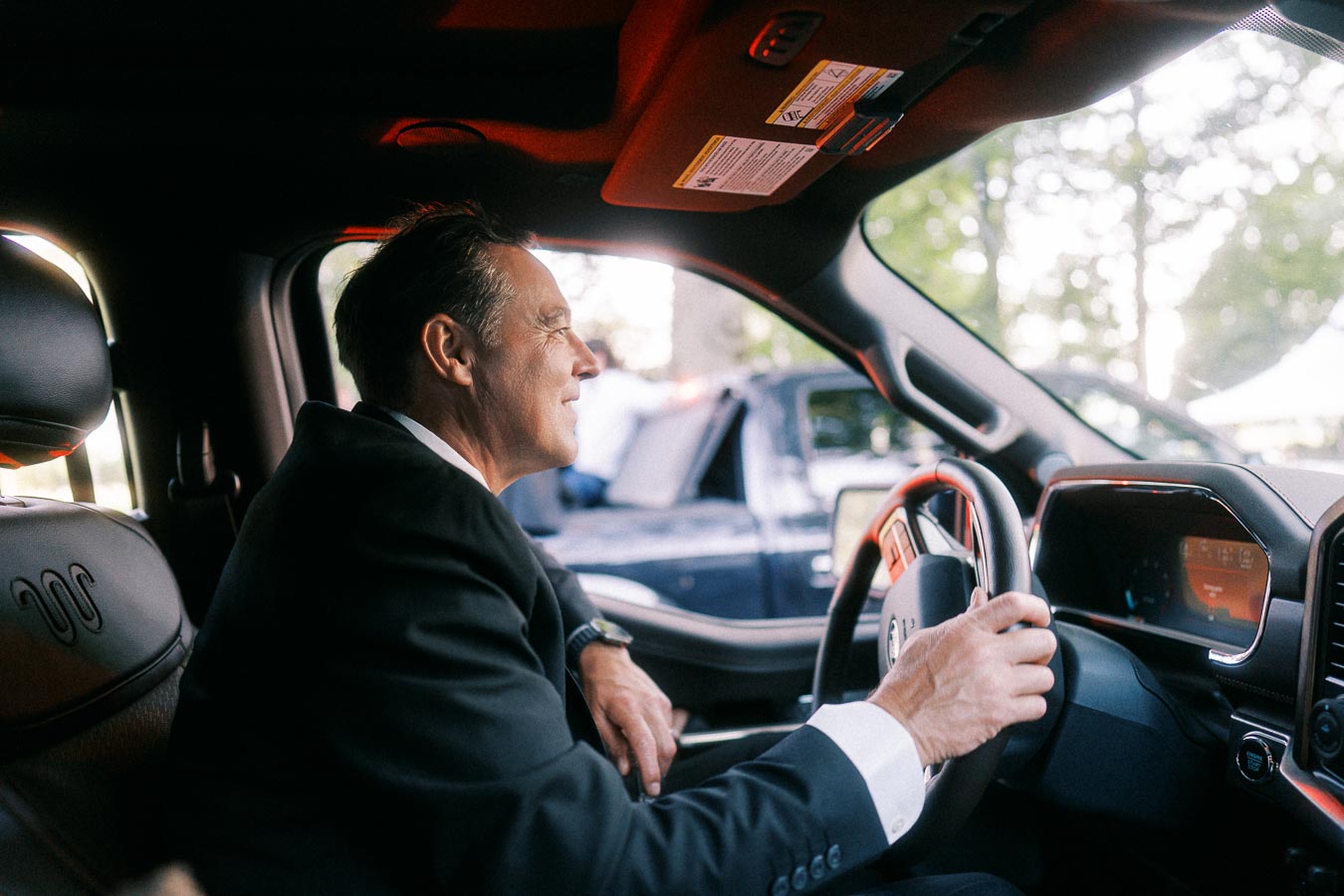 Man in a black suit sitting in the driver seat of a Jeep vehicle near Chatham-Kent, Ontario, Canada, during an outdoor private estate wedding day.