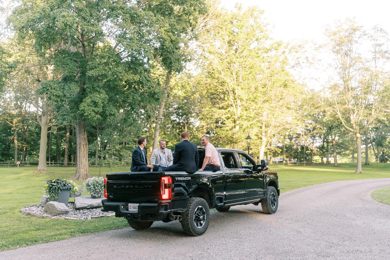 Men sitting in the bed of a black Ford Super Duty pickup on a tree lined private estate driveway near Chatham-Kent, Ontario.