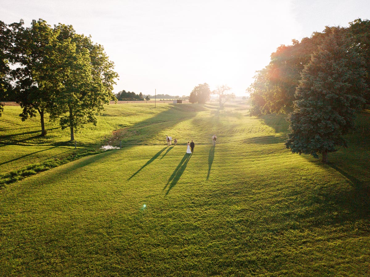 Outdoor farm wedding portrait session on a private estate lawn near Chatham-Kent, Ontario, with couple and guests at golden hour.