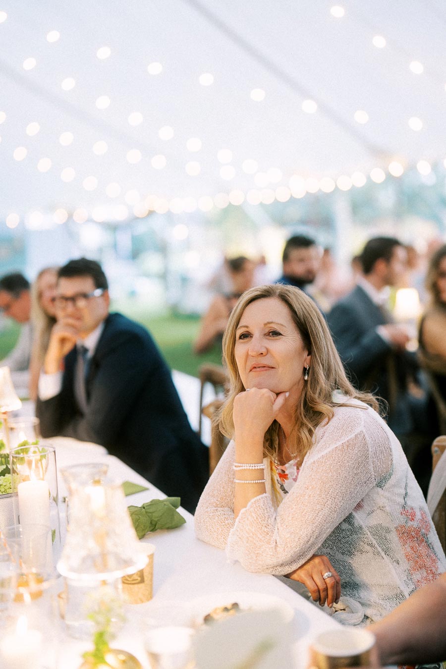 Wedding guests seated at a long dinner table under a white tent with string lights near Chatham-Kent, Ontario, Canada.