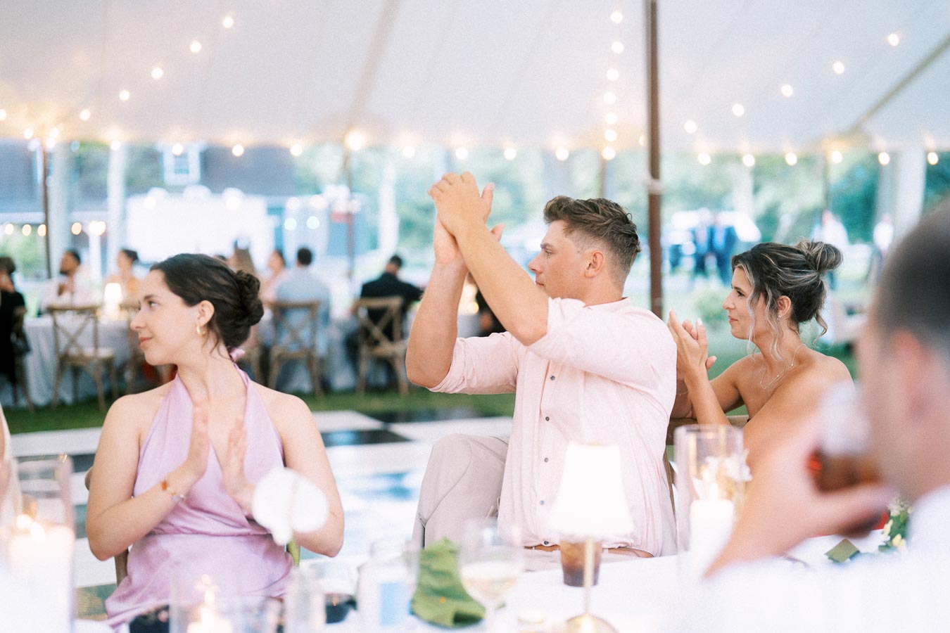 Guests applauding during a tented outdoor wedding dinner near Chatham-Kent, Ontario, Canada.