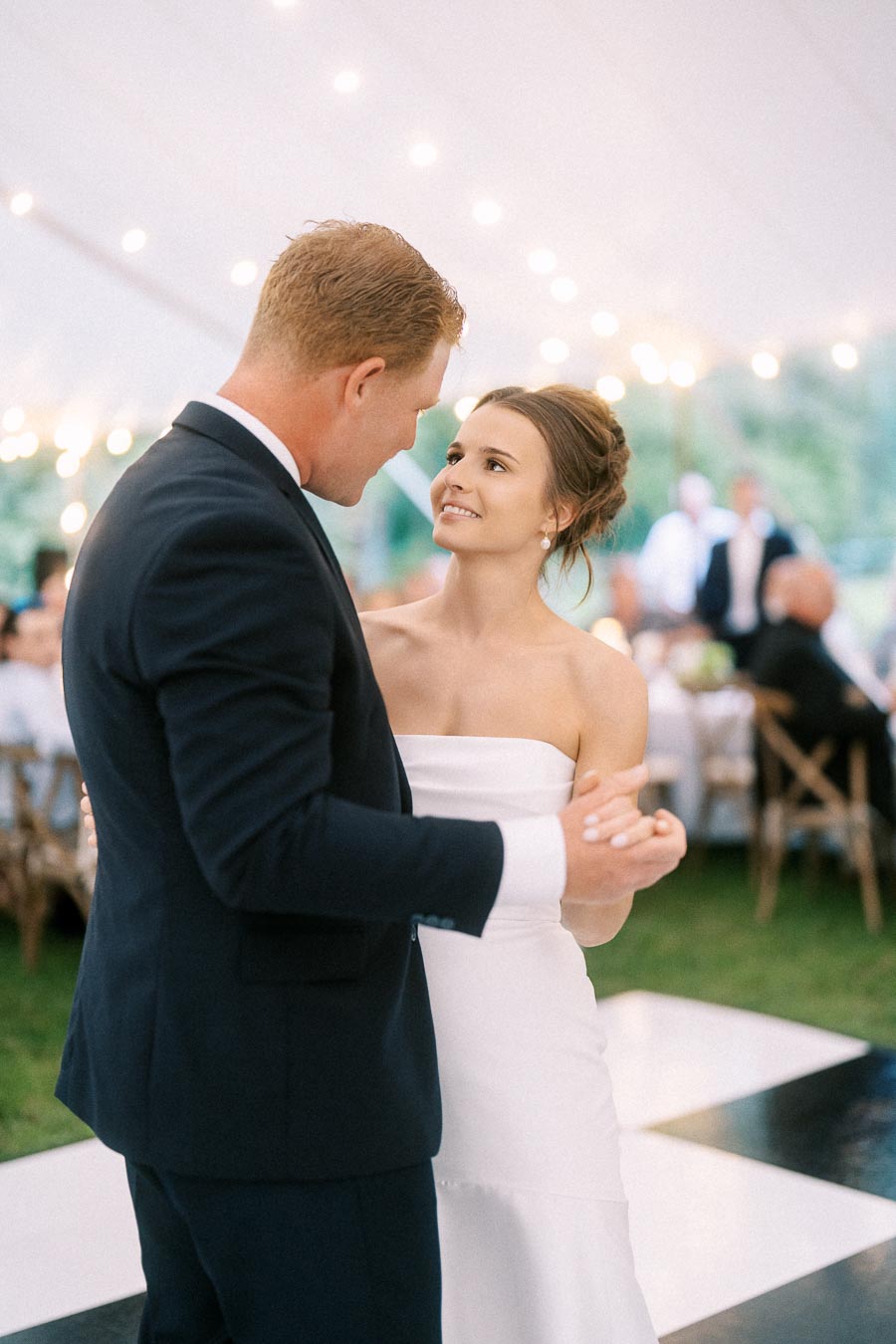 Bride and groom dancing under string lights during a tented farm wedding reception near Chatham-Kent, Ontario, Canada.
