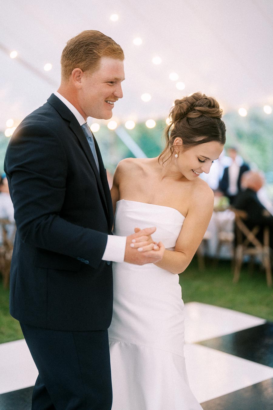 Bride and groom dancing under a white wedding tent with string lights during an outdoor farm wedding near Chatham-Kent, Ontario, Canada.