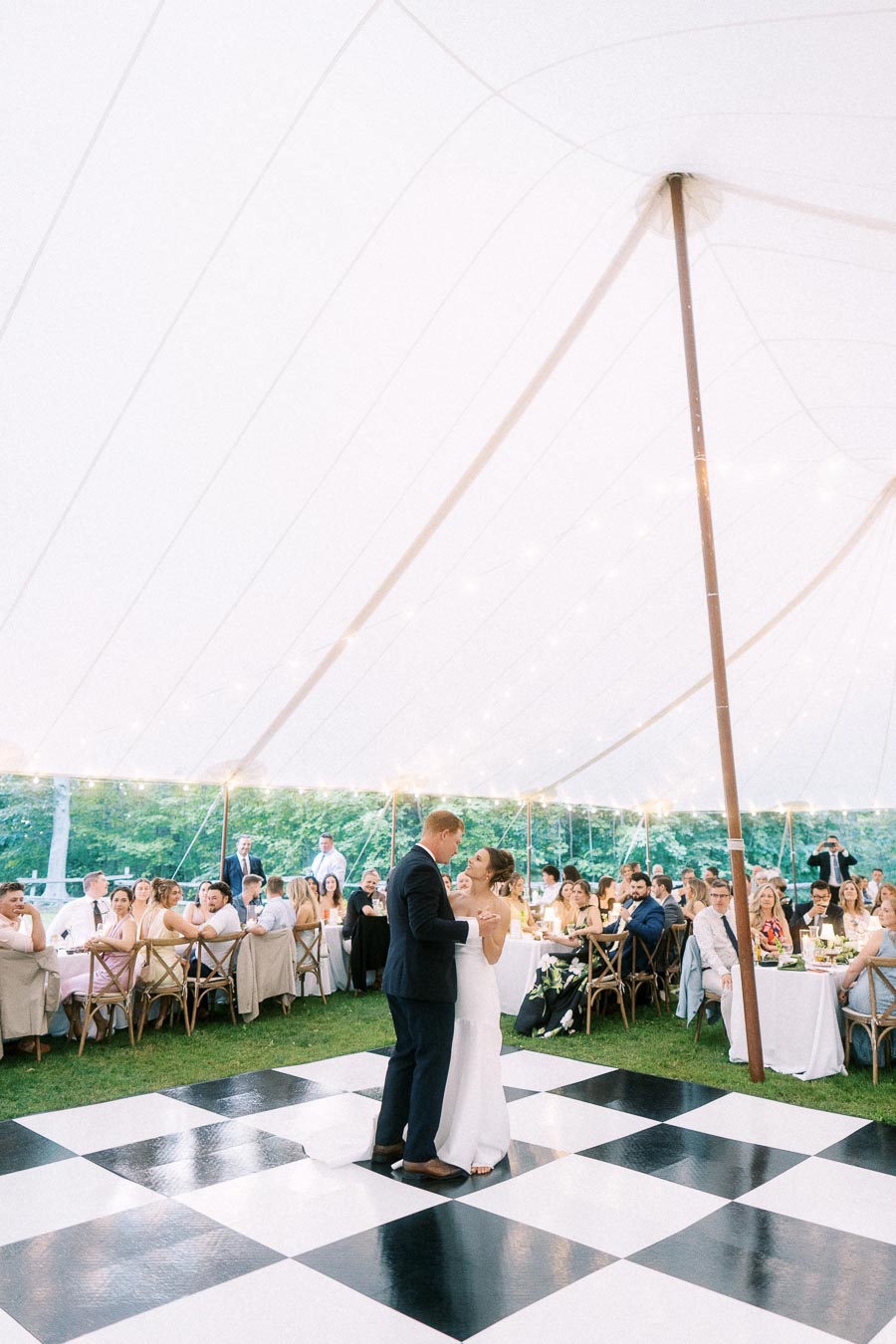 Bride and groom share a first dance on a black and white checkered dance floor during a tented farm wedding near Chatham-Kent, Ontario, Canada.