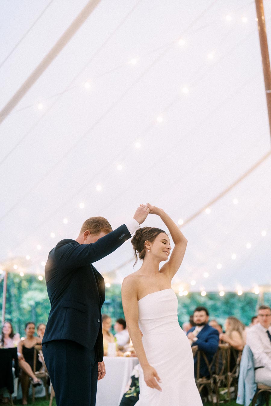 Bride and groom dancing under a white tent with string lights during an outdoor wedding reception near Chatham-Kent, Ontario, Canada.