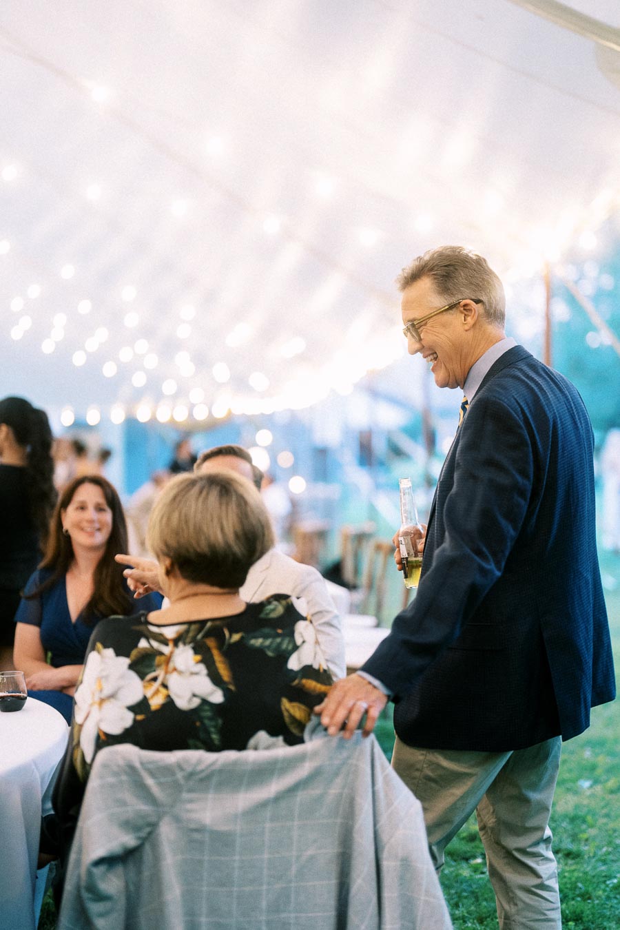 Wedding guests talking and laughing during a tented outdoor reception on a private farm estate near Chatham-Kent, Ontario, Canada.