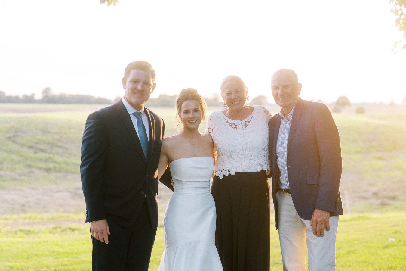 Bride, groom, and family pose outdoors at a private farm estate wedding near Chatham-Kent, Ontario, Canada, in warm sunset light.