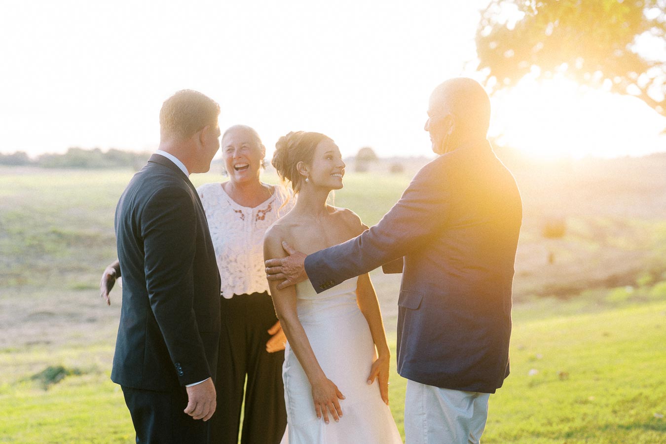 Bride and wedding guests talking outdoors at sunset on a farm near Chatham-Kent, Ontario, Canada.