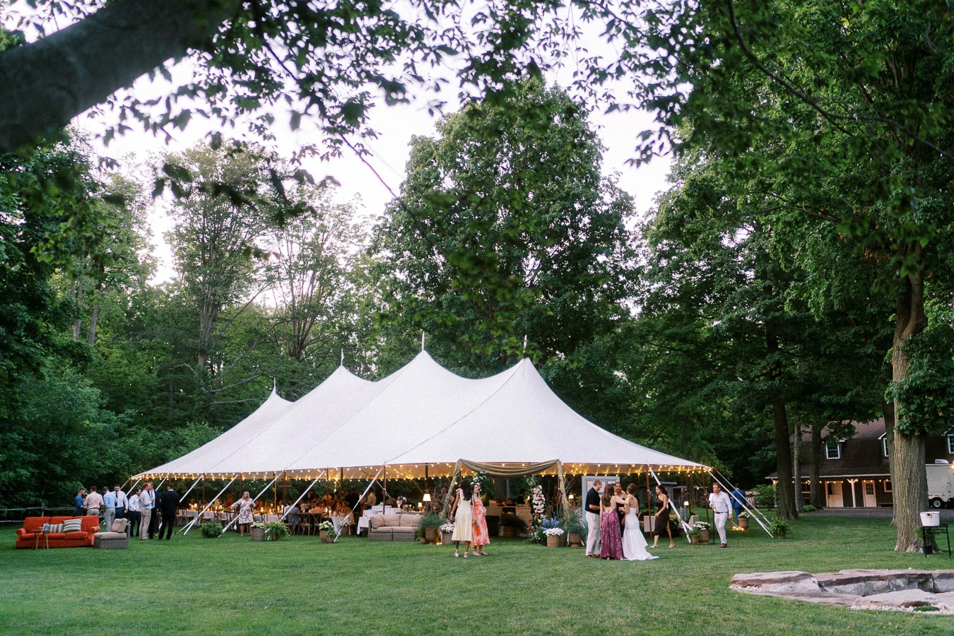 Outdoor tented wedding reception on a private farm estate near Chatham-Kent, Ontario, with guests gathered on a lawn under trees.