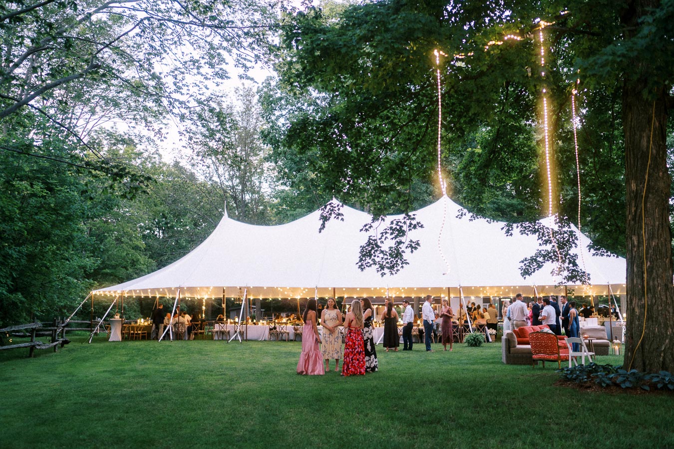 Outdoor tented wedding reception on a private estate lawn near Chatham-Kent, Ontario, with guests gathered under string lights at dusk.