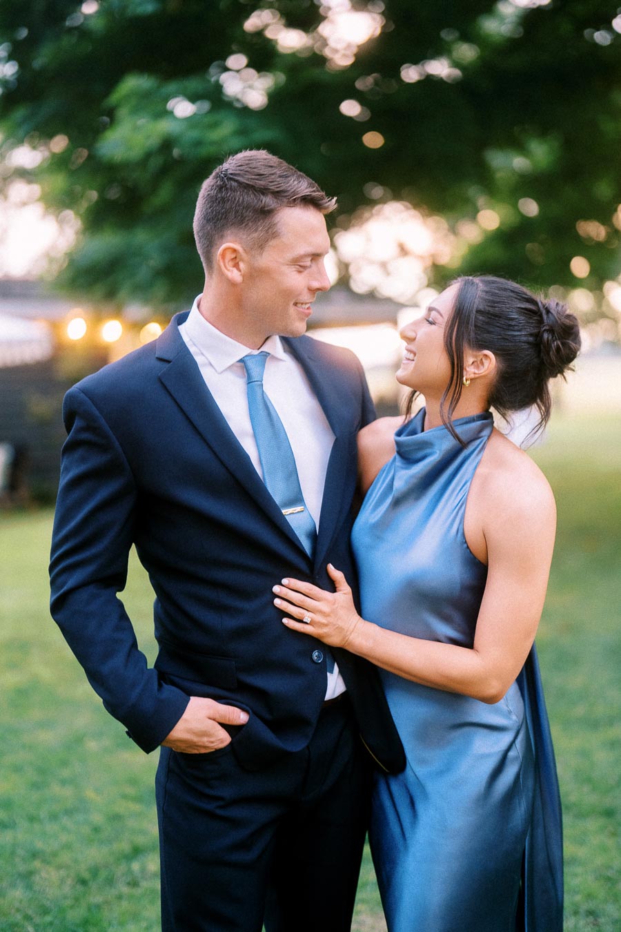 Elegant couple smiling together outdoors at a private estate wedding near Chatham-Kent, Ontario, with soft evening light and green trees.