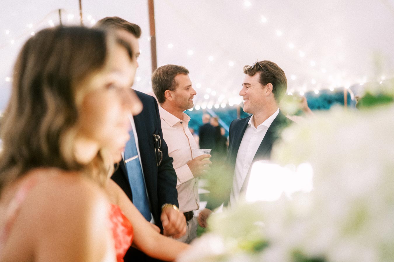 Wedding guests socialize during a tented outdoor reception on a private farm estate near Chatham-Kent, Ontario, Canada.