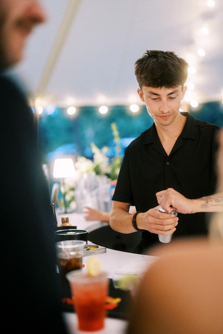 Bartender mixing cocktails at an outdoor tented wedding reception on a private farm estate near Chatham-Kent, Ontario, Canada.
