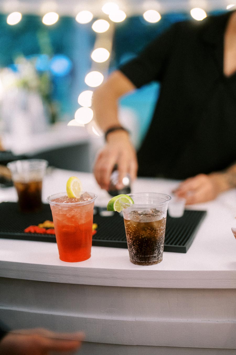 Bartender preparing mixed drinks in plastic cups at an outdoor tented wedding bar near Chatham-Kent, Ontario.