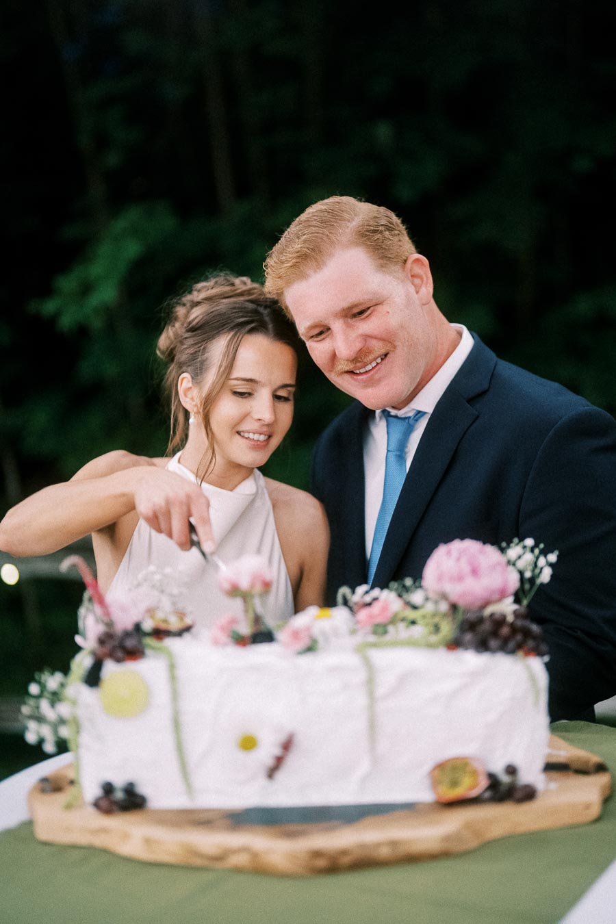 Bride and groom cutting a decorated wedding cake outdoors at a private estate farm wedding near Chatham-Kent, Ontario, Canada.