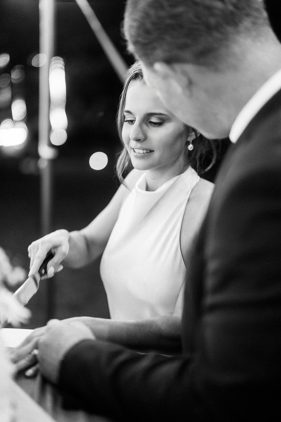 Black and white photo of a bride and groom cutting wedding cake at an outdoor tented reception near Chatham-Kent, Ontario.
