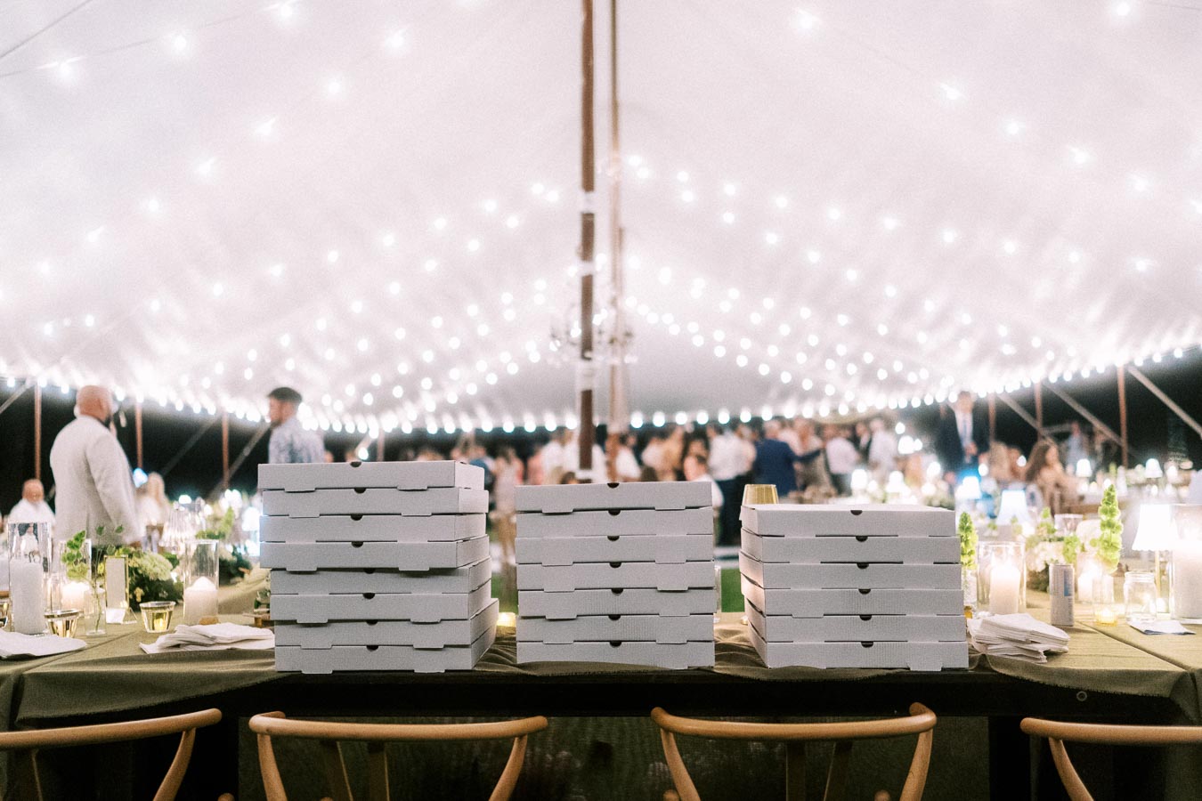 White pizza boxes stacked on a reception table inside a glowing tent at a private estate farm wedding near Chatham-Kent, Ontario, Canada.