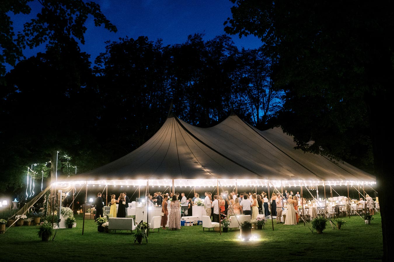 Outdoor tented wedding reception at night on a private farm estate near Chatham-Kent, Ontario, Canada, with guests under a lit marquee tent.