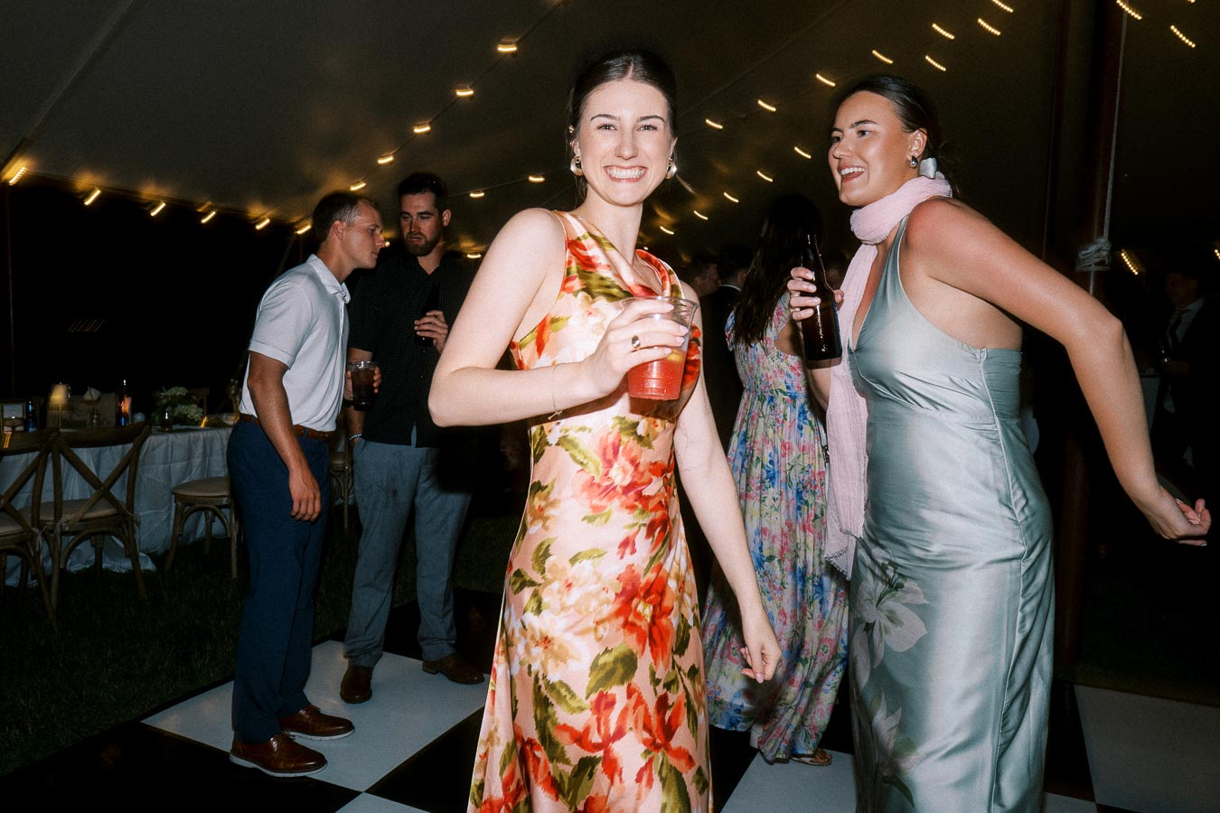 Wedding guests dancing and holding drinks under a lit reception tent at a private farm estate near Chatham-Kent, Ontario, Canada.