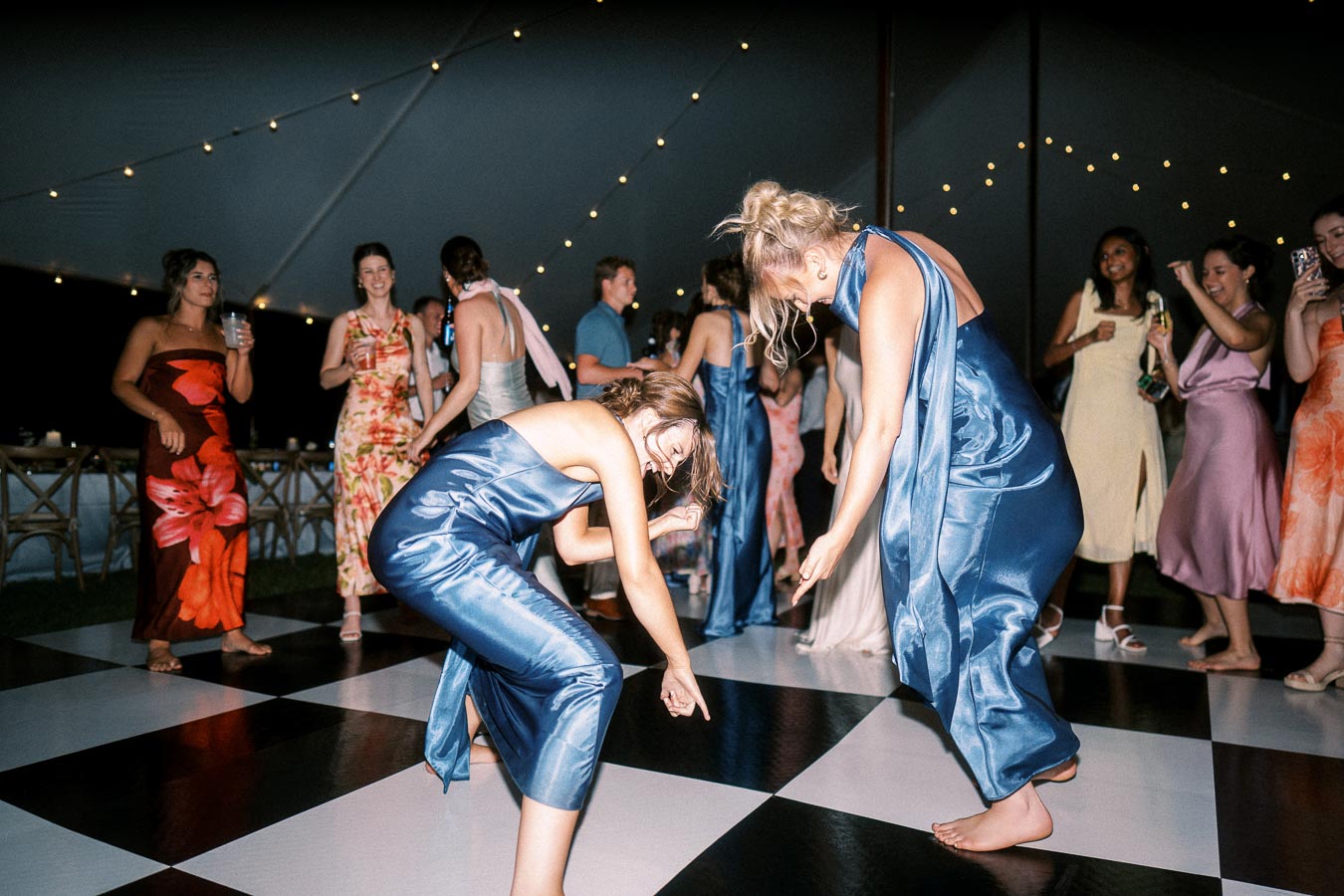 Wedding guests dancing on a checkered dance floor under string lights inside a tent near Chatham-Kent, Ontario, Canada.