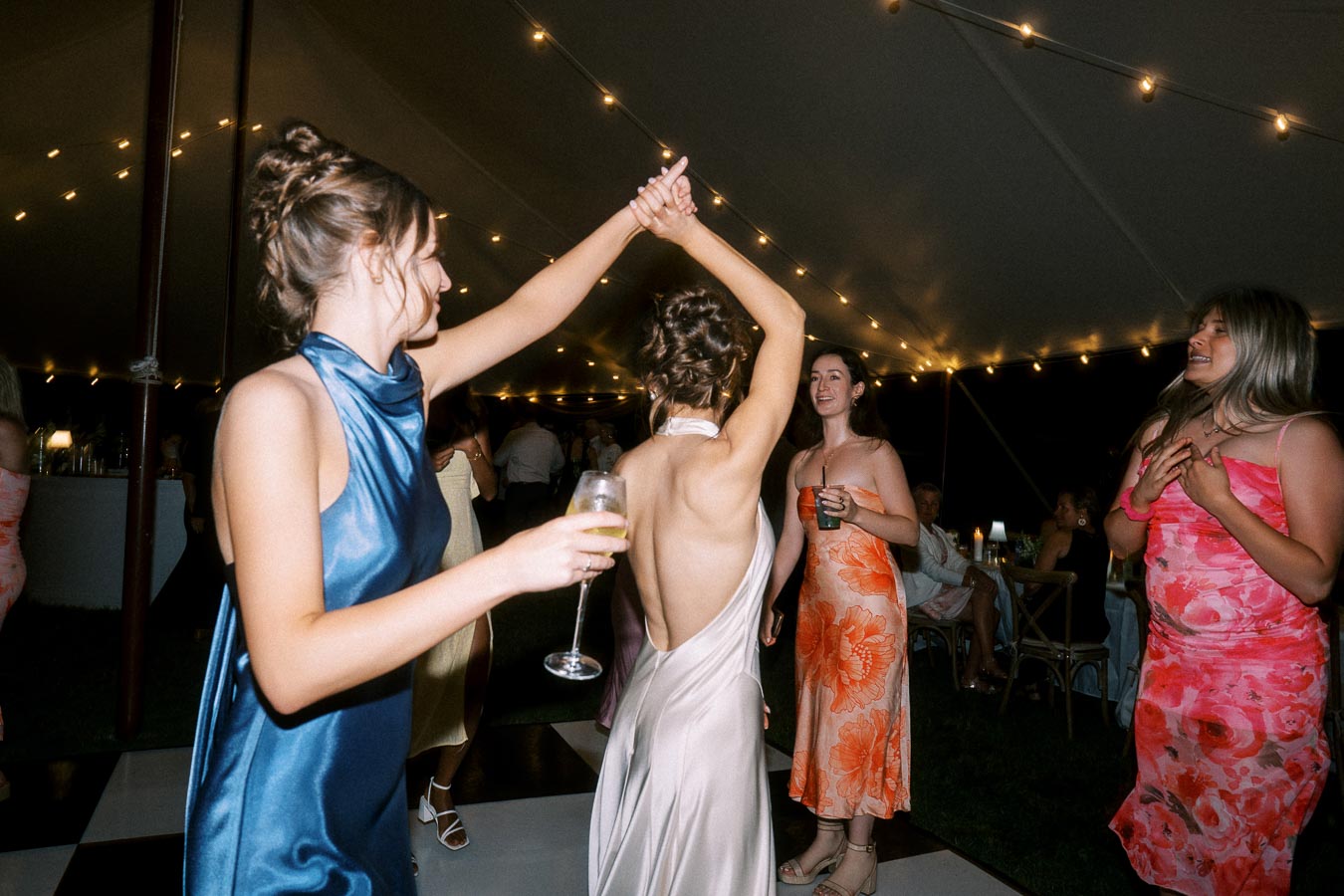 Wedding guests dance under string lights inside a tent at an outdoor private estate wedding near Chatham-Kent, Ontario, Canada.