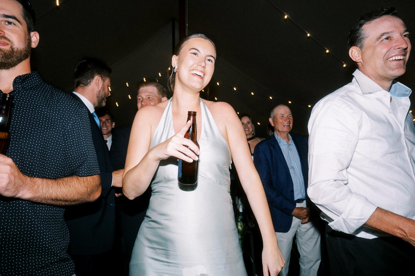 Wedding guests dancing inside a tented reception near Chatham-Kent, Ontario, with string lights and drinks on a private farm estate.