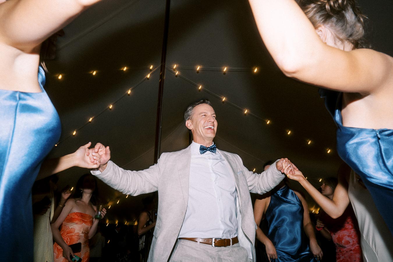 Wedding guests dancing inside a tent with string lights during an outdoor private estate celebration near Chatham-Kent, Ontario, Canada.