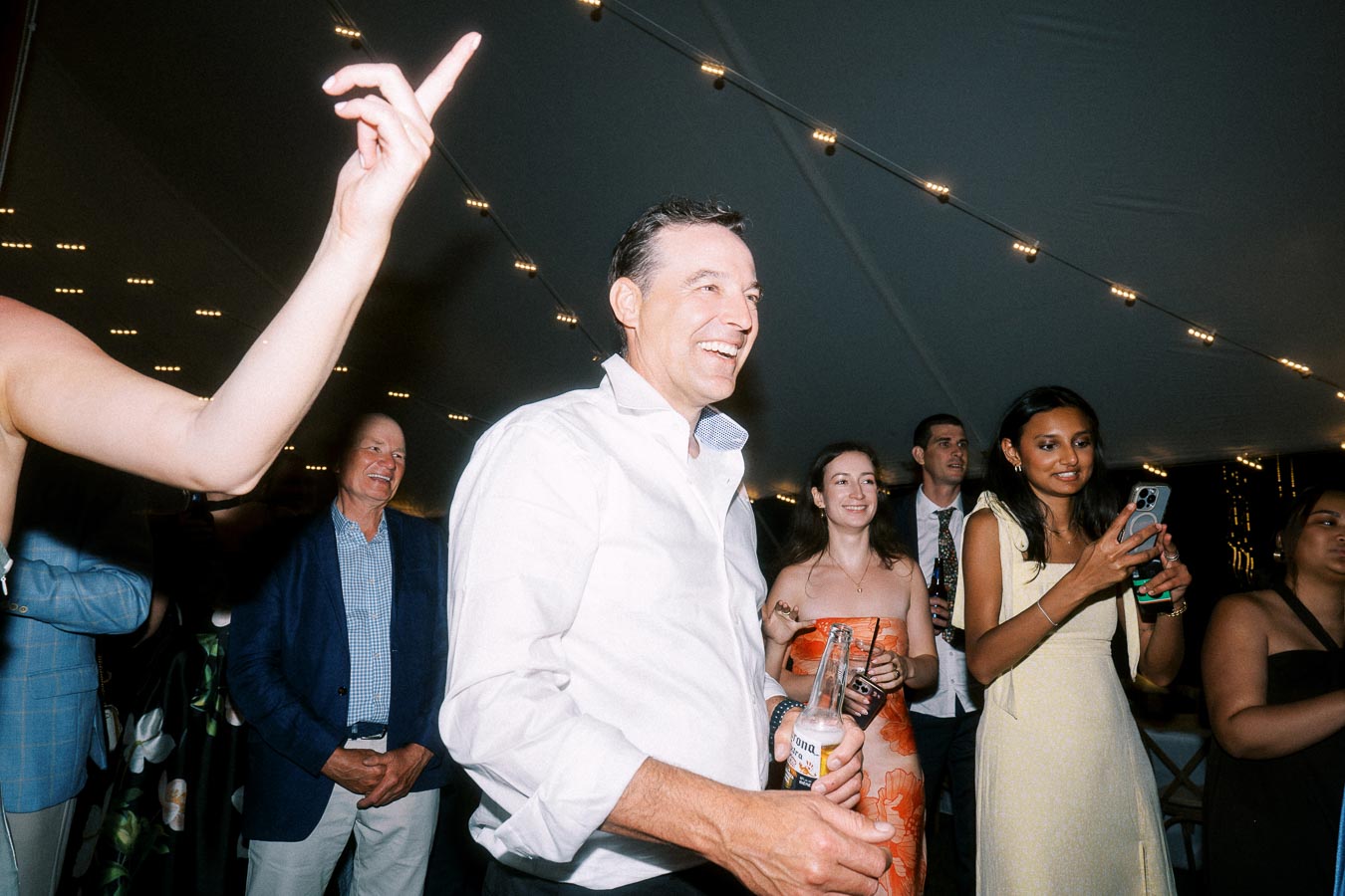 Wedding guests dancing under string lights inside a tent at a private estate farm wedding near Chatham-Kent, Ontario, Canada.