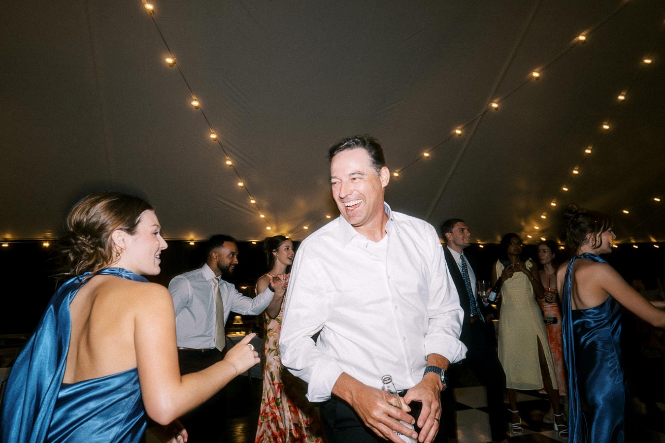 Wedding guests dancing under string lights inside a reception tent near Chatham-Kent, Ontario, Canada.