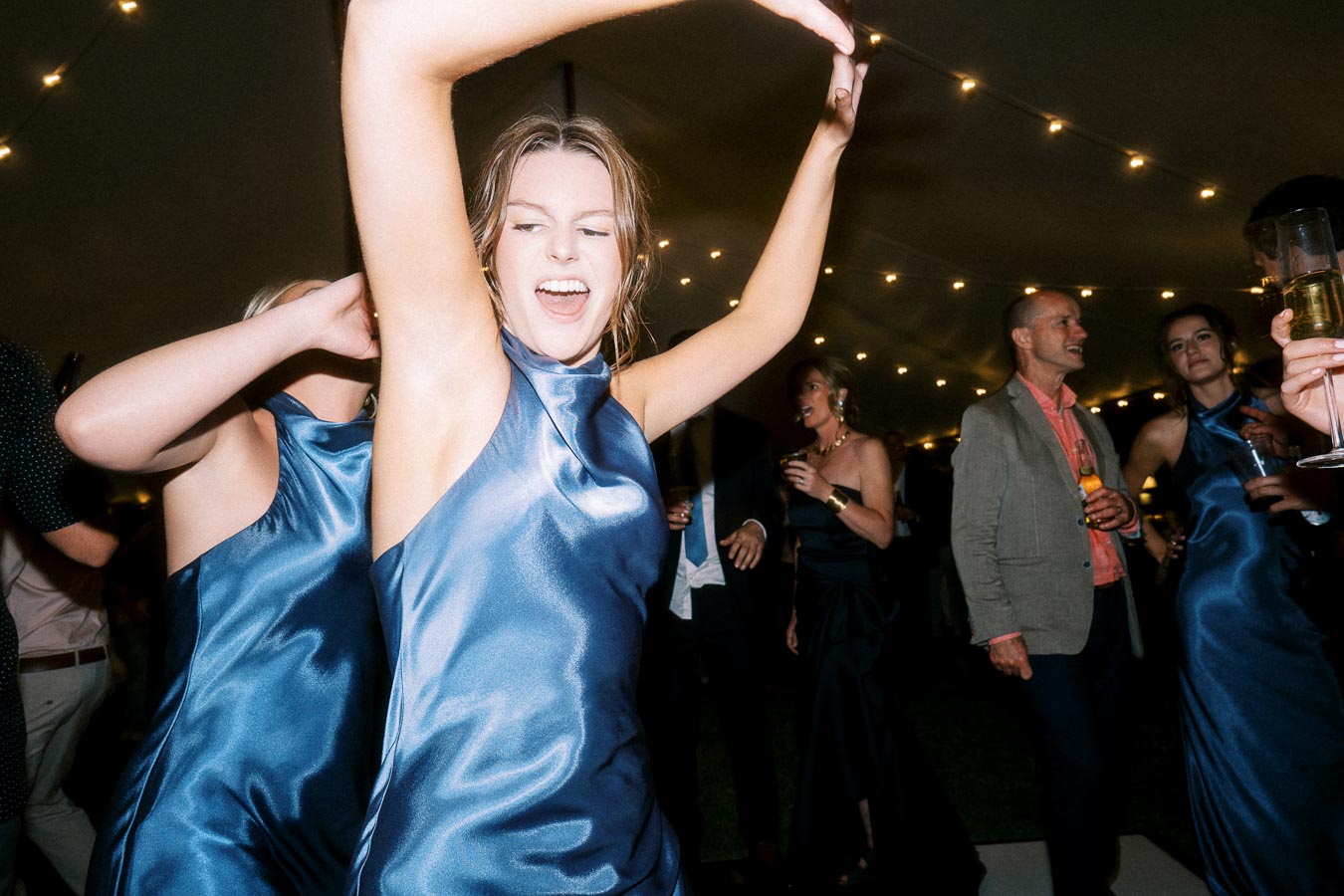 Wedding guests dancing under string lights inside a reception tent during a private estate farm wedding near Chatham-Kent, Ontario, Canada.