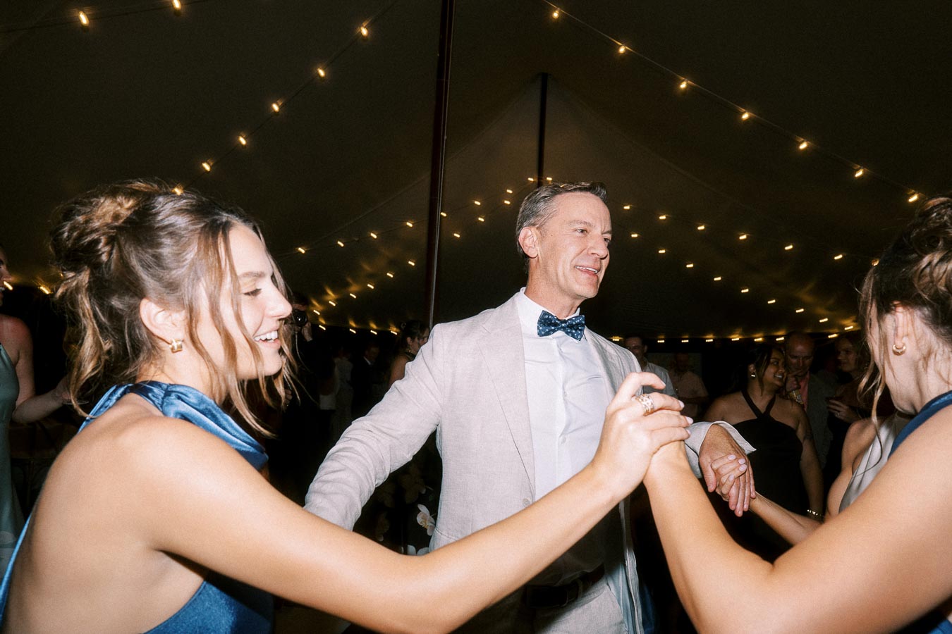 Wedding guests dancing inside a tented reception with warm string lights near Chatham-Kent, Ontario, Canada.
