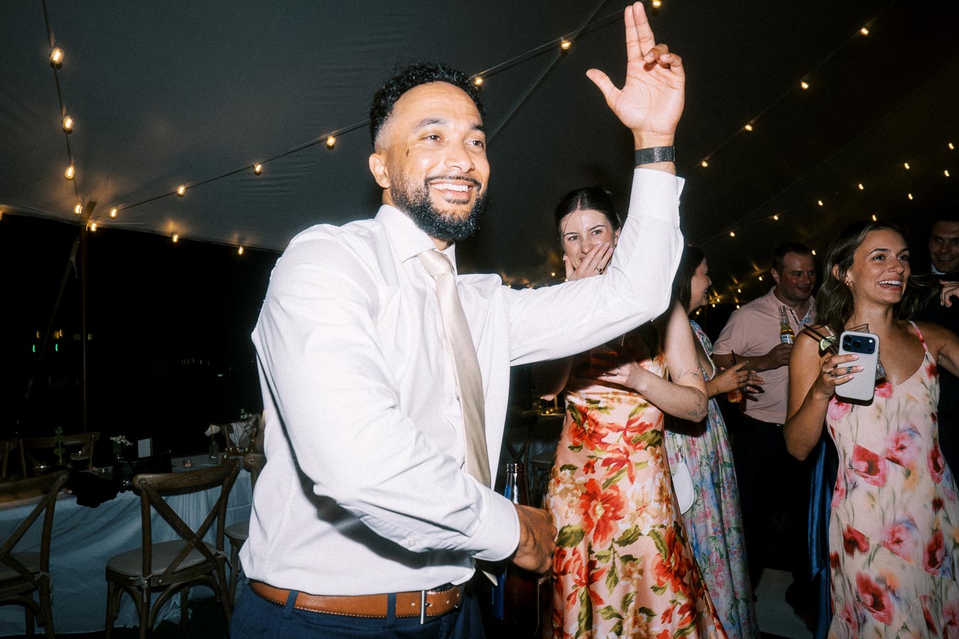 Wedding guests dancing under string lights inside a tent during a private estate farm wedding near Chatham-Kent, Ontario, Canada.