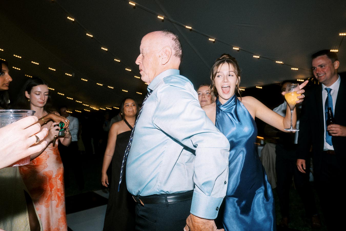 Wedding guests dancing under a tent with string lights during a private estate reception near Chatham-Kent, Ontario, Canada.