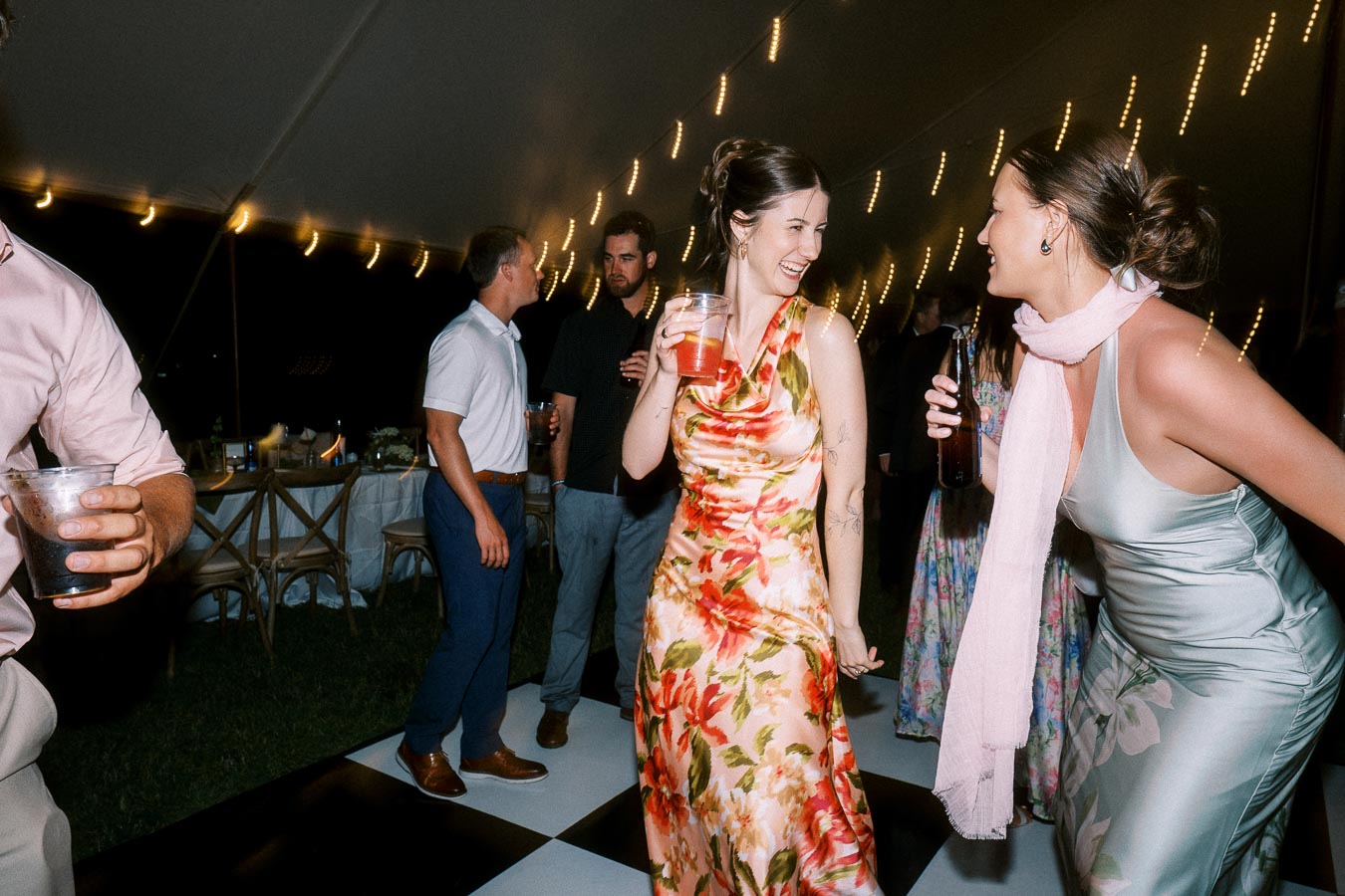 Wedding guests dancing and laughing under string lights inside a reception tent at a private farm estate near Chatham-Kent, Ontario, Canada.