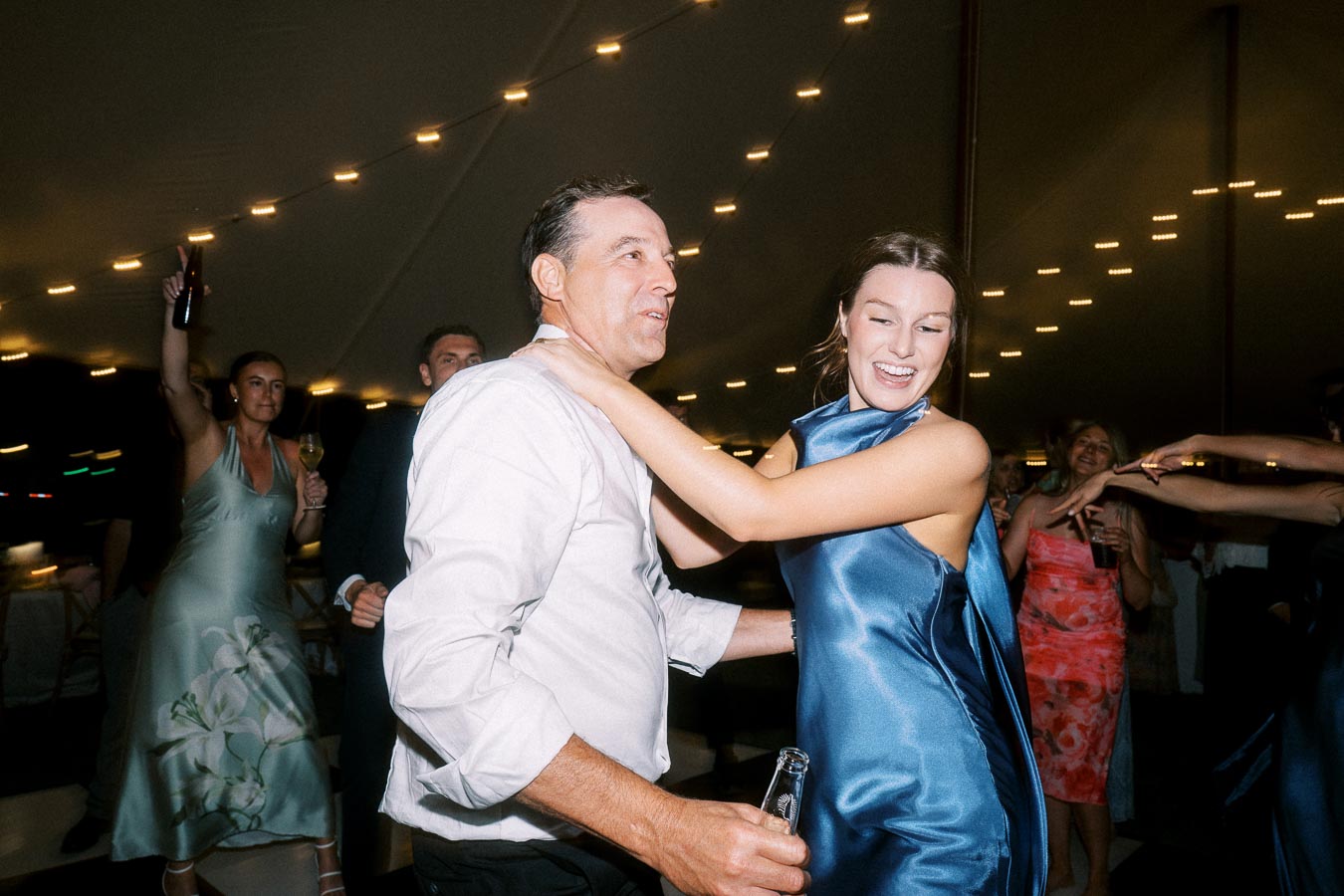 Wedding guests dancing under string lights inside a reception tent at a private estate farm wedding near Chatham-Kent, Ontario, Canada.