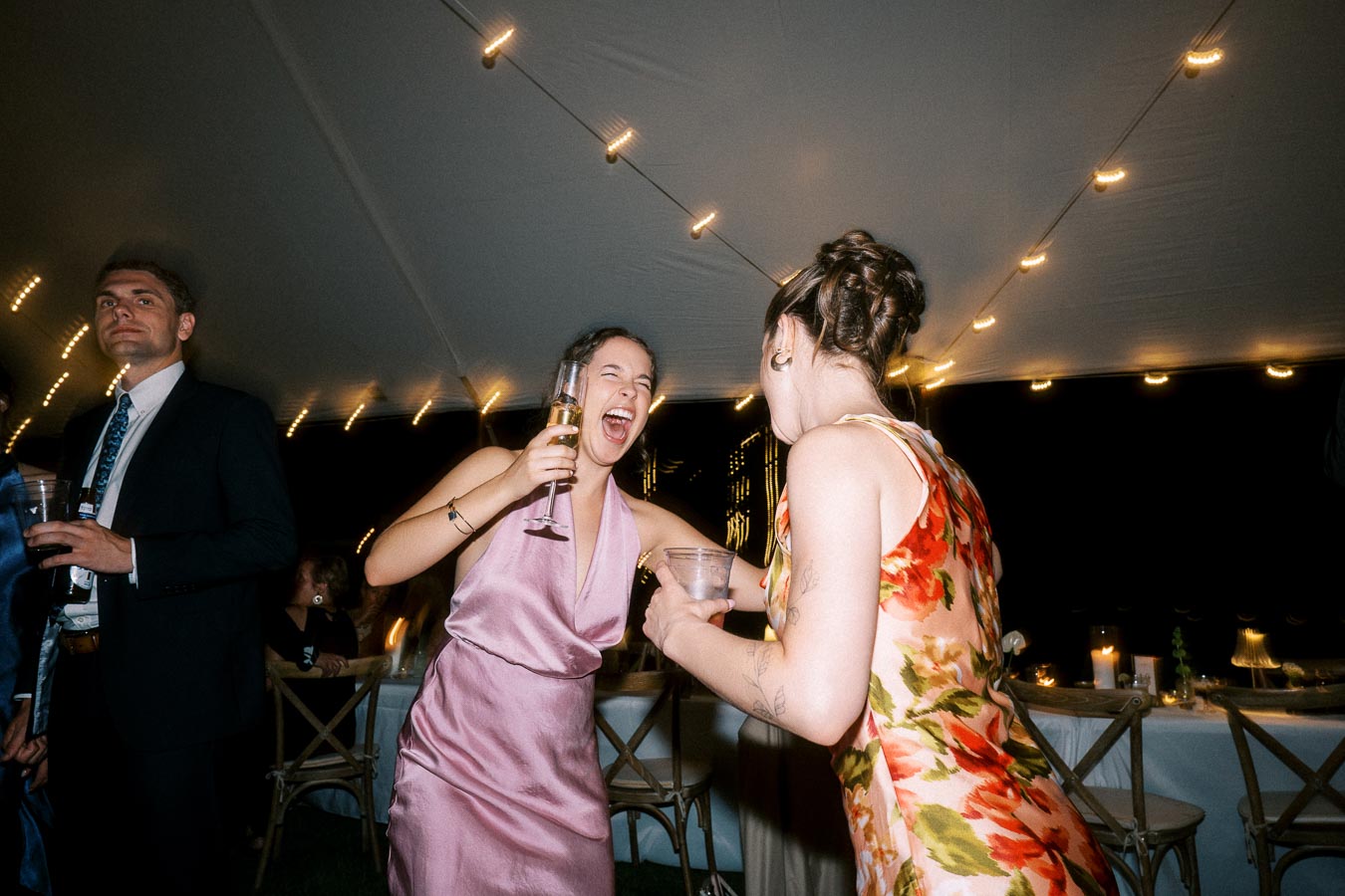 Wedding guests laughing and dancing under a lit reception tent at a private farm estate near Chatham-Kent, Ontario, Canada.