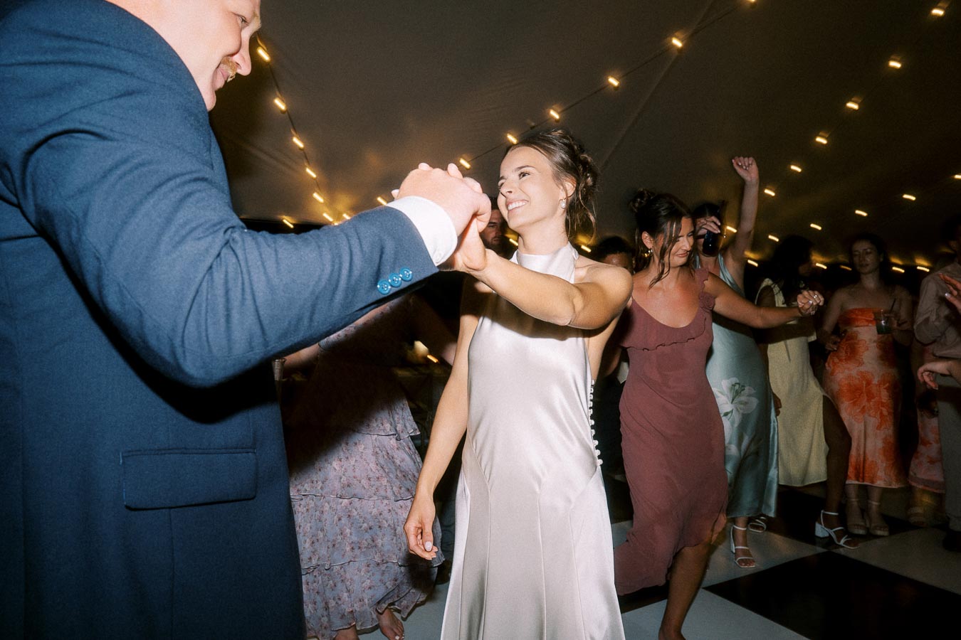 Bride dancing with guests under string lights inside a wedding tent near Chatham-Kent, Ontario, Canada.