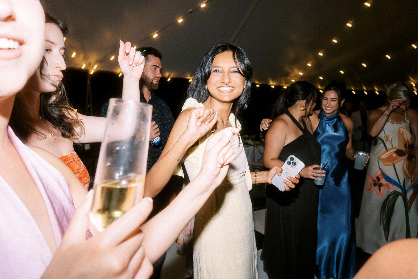 Wedding guests dancing under a tent with string lights during an outdoor private estate farm wedding near Chatham-Kent, Ontario, Canada.