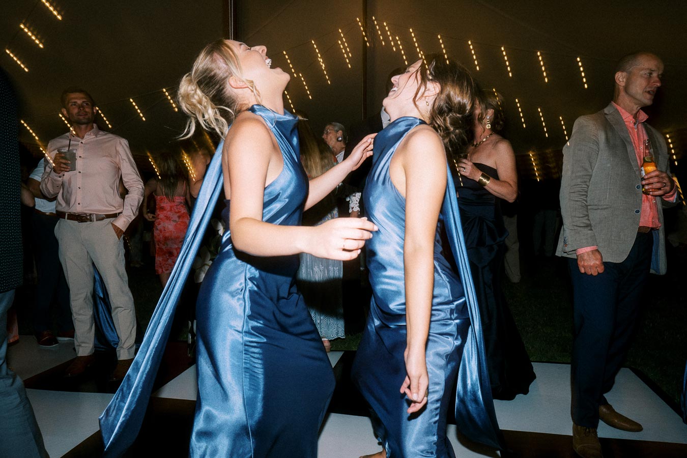 Wedding guests laughing and dancing under a tent with string lights near Chatham-Kent, Ontario, Canada.