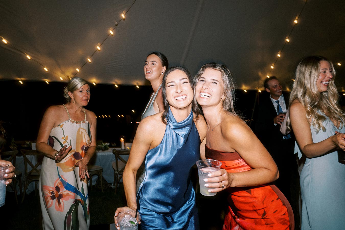 Wedding guests smiling and dancing under a tent with string lights at an outdoor private estate celebration in Chatham-Kent, Ontario, Canada.