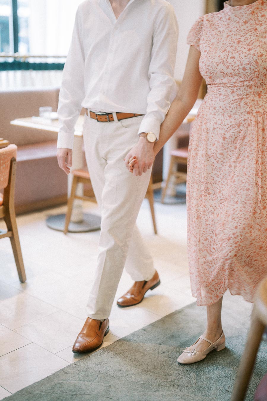 Couple holding hands while walking through a bright Toronto restaurant interior