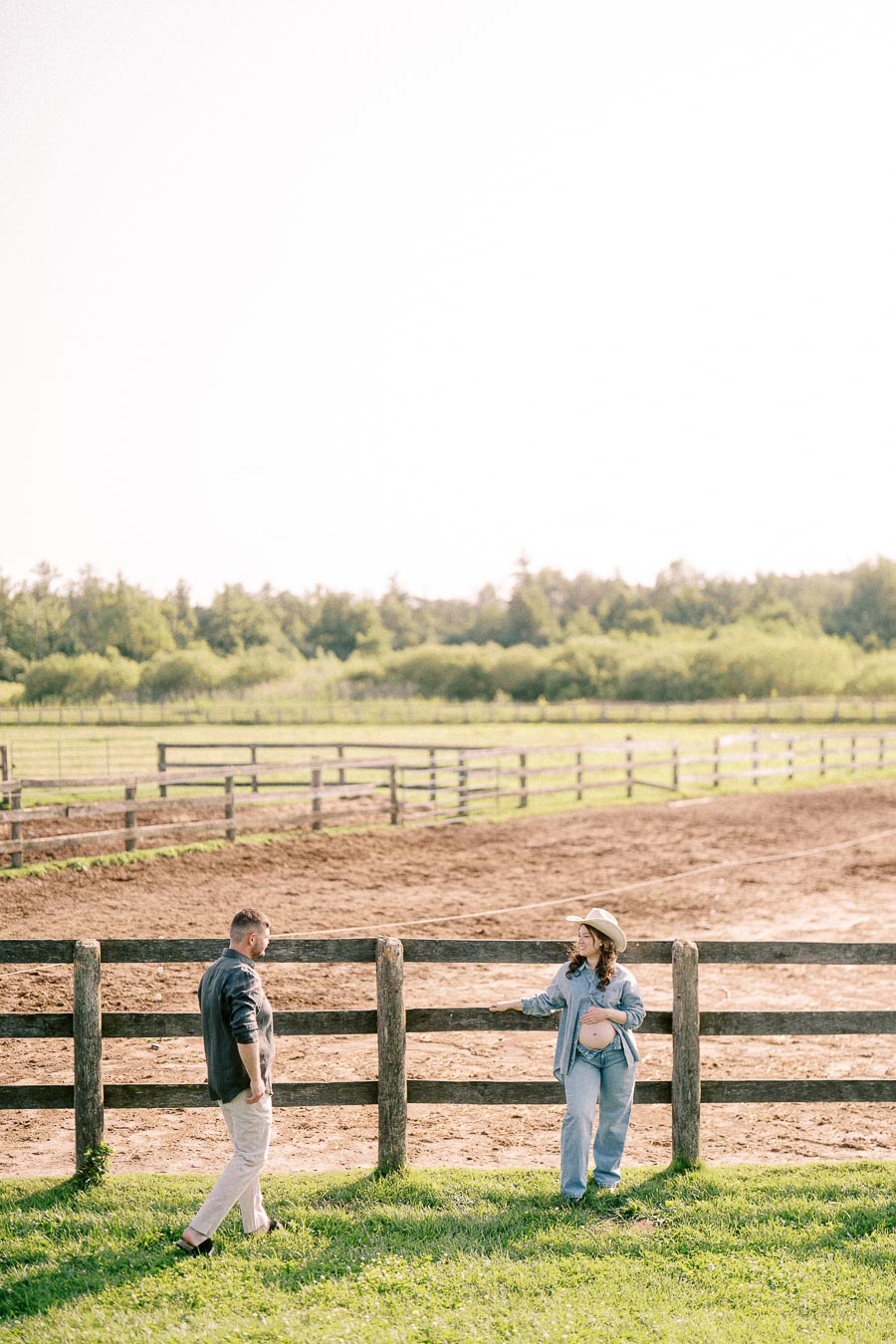 Expectant couple by a wooden paddock fence at The Green Acres in Flamborough