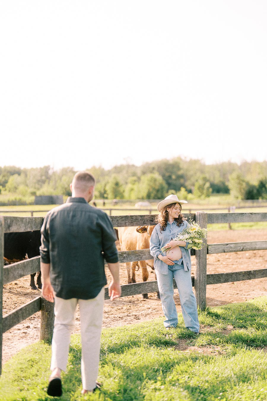 Pregnant woman holding flowers by a horse paddock at The Green Acres