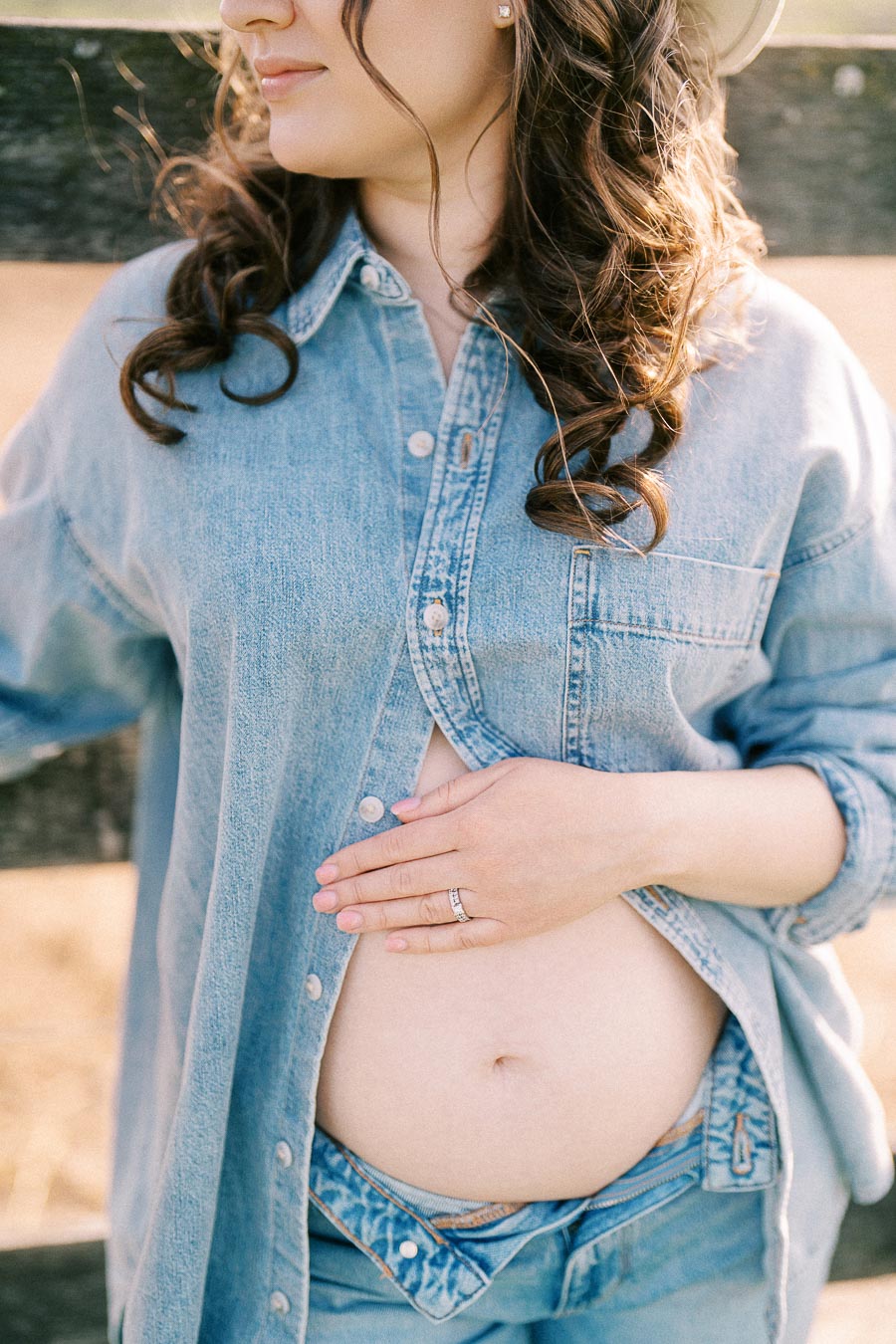 Expectant mother in denim resting a hand on her baby bump