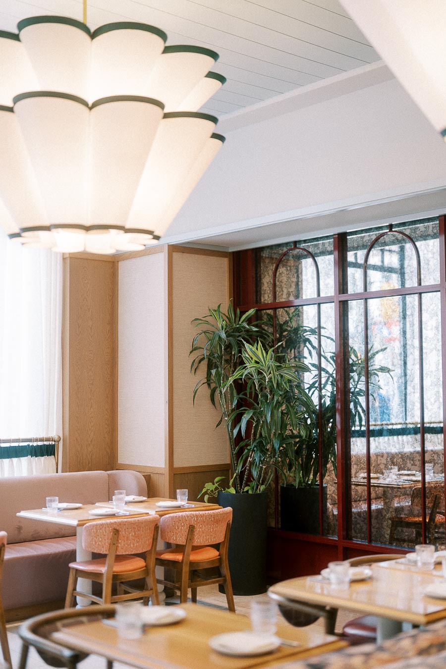 Elegant Toronto restaurant dining room with sculptural lights, plants, and set tables