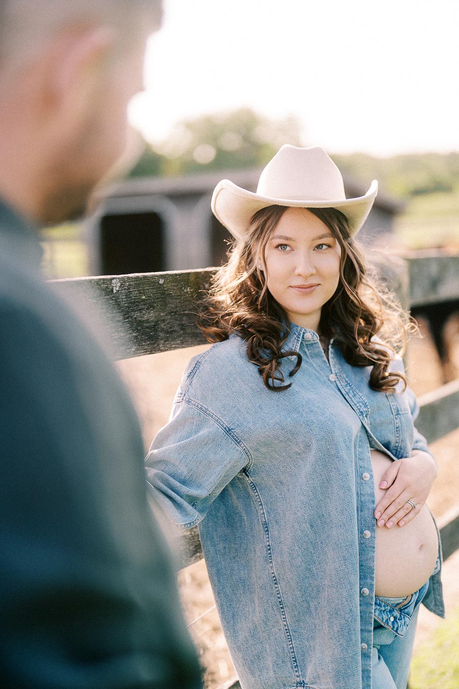 Pregnant woman in a cowboy hat by a wooden fence at The Green Acres